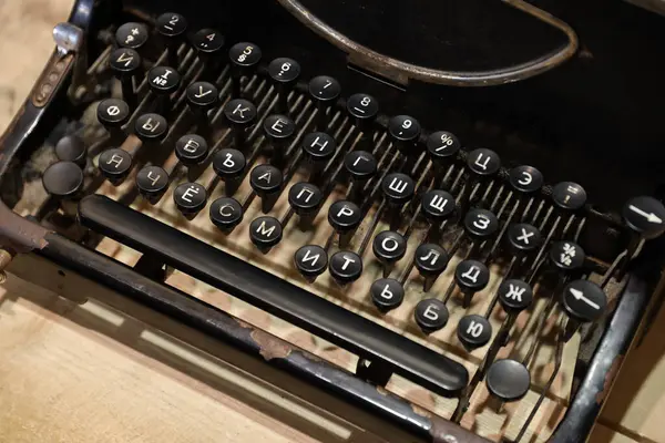 Details of an old retro typewriter in vintage style with dusty surfaces on wooden table in dark interior