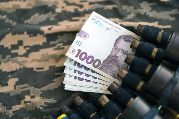 Ukrainian army machine gun belt shells and bunch of hryvnia bills on military uniform. Payments to soldiers of the Ukrainian army, salaries to the military. War in Ukraine