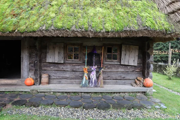 Three different brooms of witches stand at the old wooden hut house close up