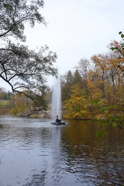 Gölü olan güzel tabiat sonbahar manzarası. Bulutlu bir günde altın sarısı yeşilliklerle sonbahar şehir parkının manzarası. Sonbahar yapraklarıyla kaplı Park 'ta yürüyüş yolları.