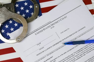 Bölge mahkemesi dava bildirisi ve mahkeme celbinden feragat talebinde bulundu. Elleri kelepçeli kağıtlar ve mavi kalemle ABD bayrağını kapatın.