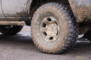 Çamur yolu olan bir kırsal alanda tekerlek yakın çekim. Off-road 4x4 SUV otomobil çamurlu yol alanında sürdükten sonra ditry body ile