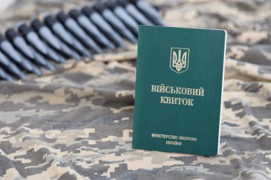 Piksel kamuflaj dokusuna sahip kumaş üzerinde Ukrayna askeri kimliği. Gri, kahverengi ve yeşil pikselli kamuflaj desenli kumaş Ukrayna ordusunun kişisel jetonu ve makineli tüfek kemeri.