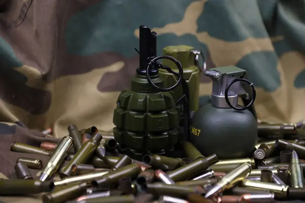 Different types of ammunition and grenades on a camouflage background. Preparing for war. Possession of weapons