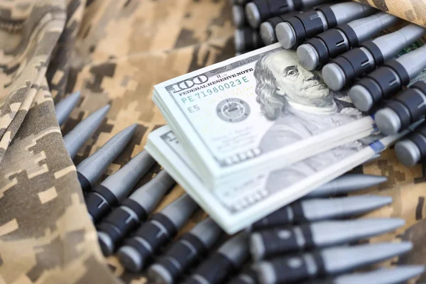 Bundles of dollars and a machine gun belt on the camouflage uniform of a Ukrainian soldier. Concept of war financing, bribe or donation. Help to Ukraine from the USA