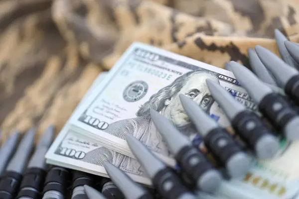Bundles of dollars and a machine gun belt on the camouflage uniform of a Ukrainian soldier. Concept of war financing, bribe or donation. Help to Ukraine from the USA