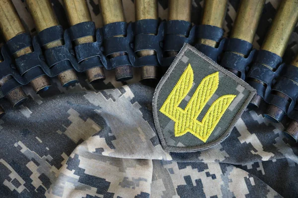 Ukrainian army symbol on machine gun belt lies on ukrainian pixeled military camouflage close up
