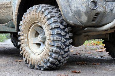Çamur yolu olan bir kırsal alanda tekerlek yakın çekim. Off-road 4x4 SUV otomobil çamurlu yol alanında sürdükten sonra ditry body ile