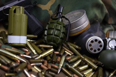Kamuflaj arka planında farklı cephane ve el bombaları var. Savaşa hazırlanıyorum. Silah bulundurma.