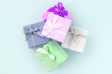 Küçük renkli hediye kutuları şeritler yığını mor bir arka plan üzerinde yatıyor. Üstten görünüm minimalizm düz yatıyordu.