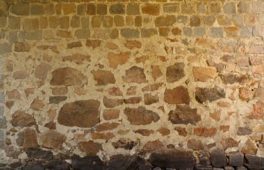 Texture of a stone wall with many big brown and grey stones armed with cement. Old castle stone wall texture background for medieval usage. Part of a stony building as a background