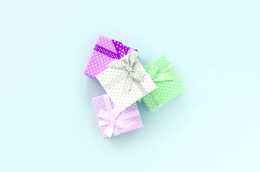 Küçük renkli hediye kutuları şeritler yığını mor bir arka plan üzerinde yatıyor. Üstten görünüm minimalizm düz yatıyordu.