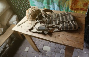 Bir Ukraynalı askerin askeri miğferi ağır kurşun geçirmez yelek ile kontrol noktası iç kısımlarındaki ahşap masada.