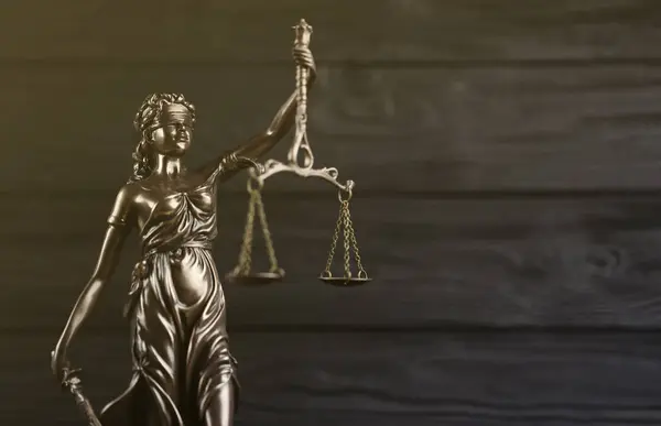The Statue of Justice - lady justice or justitia the Roman goddess of Justice. Statue on black wooden wall. Concept of judicial trial, courtroom process and lawyers occupation