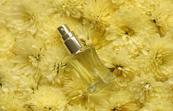 Women fragrance perfume bottle with flowers background close up. Unnamed blank sprayer bottle of perfume for women
