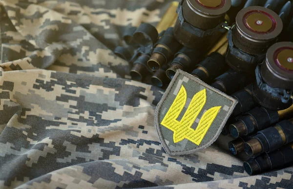 Ukrainian army symbol on machine gun belt lies on ukrainian pixeled military camouflage close up