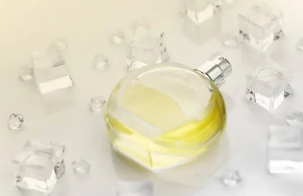 Female perfume yellow bottle, Objective photograph of perfume bottle in ice cubes and water on white table. View from above. Mockup product photo, concept of freshness and aroma