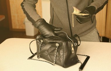 Siyah kıyafetli ve eldivenli soyguncu, çalıntı kadın çantasının içini görmüş. Hırsız mutfaktaki bir kadın çantasından altın ve parayı almış.