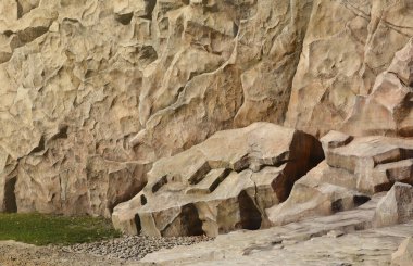 Hafif kaba doğal kaya arkaplanı. Maden kayalıkları ön yüzeye çıkıyor. Büyük bir kireçtaşı yığını. Ağır grunge hasarlı granit blok dokusu. Tasarım için antik ortaçağ taşlı cephesini kır