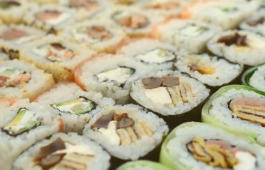 Bir sürü suşi Close-Up farklı dolguları yalanla ahşap yüzeyde alır. Bir kopya alanı ile pişmiş klasik Japon gıda makro çekim.