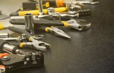 Siyah ahşap masada el işi alet çantası. Onarım ve inşaat işleri için birçok anahtar ve tornavida, sütun ve diğer aletler. Tamirci araçları ayarlandı