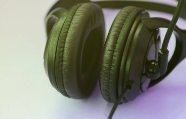Siyah kulaklık bir pastel renkli menekşe özgeçmişlerine yatıyor. Müzik dinleme konsepti