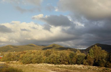 Gün doğumunda dağlarda. Sonbaharda yaprakları dökülen tarlaları ve ağaçları olan otlak kırsal yamaçlar. Sisli mesafede muhteşem bir dağ..