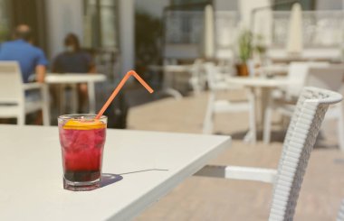 Pembe ve kırmızı renkli egzotik alkollü kokteyl. Restoran masasında limon ve buz var. Renkli pembe buzlu içecek. Kırmızı renkli Mojito.