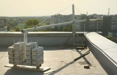 Karşı ağırlık ya da ağırlık dengesi beton bloklar ya da tuğlalar, çok katlı binalarda çalışmak üzere askıya alınmış tel halat platformunun bir parçası olarak çalışmaktadır. Metal taşıma kolu olan birçok blok