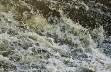 Waves of water of the river and the sea meet each other during high tide and low tide. Deep blue stormy sea water surface with white foam and waves pattern, background photo texture