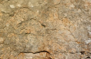 Doğal arka plan kavramları için büyük bir kaya yüzeyinin kaba taş dokusuna yakın çekim. Kirli doğal taştan arkaplan dokusu sıcak tonlarda