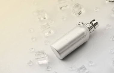 Kadın parfüm şişesi, buz küplerindeki metal parfüm şişesinin objektif fotoğrafı ve beyaz masanın üzerindeki su. Yukarıdan bak. Model ürün fotoğrafı, tazelik ve aroma konsepti
