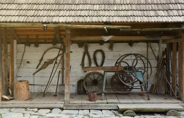 Collection of planers and retro wood saws hang on a wooden wall near an old house. Carpenters plane and other things on the wall