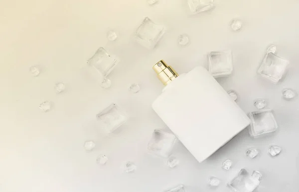 Female perfume mat white bottle, objective photograph of perfume bottle in ice cubes and water on white table. View from above. Mockup product photo, concept of freshness and aroma