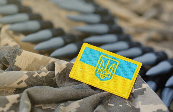 Украинский символ и пулемётный пояс на камуфляжной форме украинского солдата. Концепция войны в Украине, патриотизм и защита своей страны от российских оккупантов