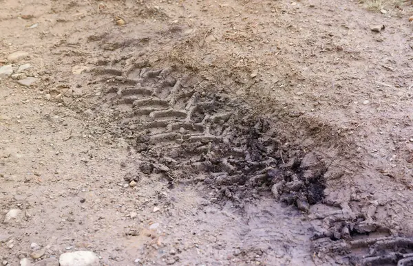 Wheel track on mud. Traces of a tractor or heavy off-road car on brown mud in a wet meadow