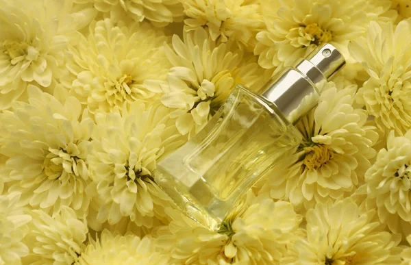 Women fragrance perfume bottle with flowers background close up. Unnamed blank sprayer bottle of perfume for women