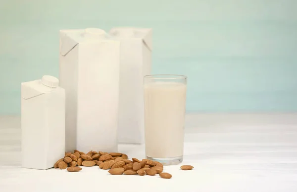 Glass of almond milk with almond nuts on canvas fabric on white wooden table. Dairy alternative milk for detox, healthy eating and diets.