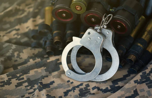 Ukrainian army machine gun belt shells and handcuffs on military uniform. Concept of bribery and war crimes.