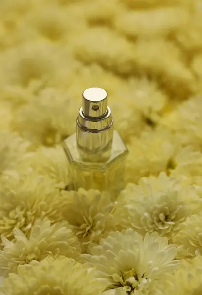 Women fragrance perfume bottle with flowers background close up. Unnamed blank sprayer bottle of perfume.