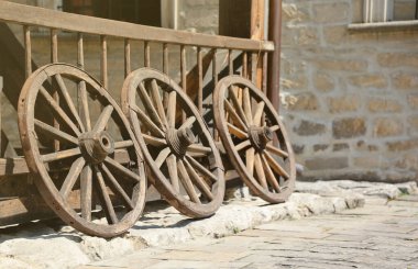 At arabaları için üç eski ahşap tekerlek Tahta duvara yaslanmış perspektifte