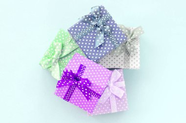 Küçük renkli hediye kutuları şeritler yığını mor bir arka plan üzerinde yatıyor. Üstten görünüm minimalizm düz yatıyordu.