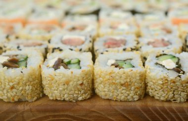 Bir sürü suşi Close-Up farklı dolguları yalanla ahşap yüzeyde alır. Bir kopya alanı ile pişmiş klasik Japon gıda makro çekim.