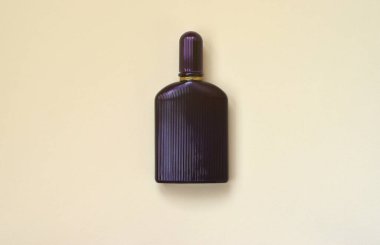 Pastel kağıdın arka planında altın kurdeleli koyu mor parfüm şişesi. Moda parfüm tasarımı