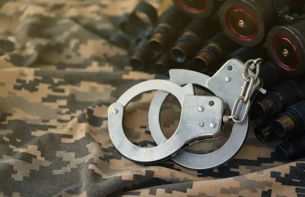 Ukrainian army machine gun belt shells and handcuffs on military uniform. Concept of bribery and war crimes during war in Ukraine