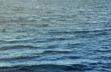 The raging waters of the river. Top view background texture of the raging elements. White foam on blue waving water in evening.