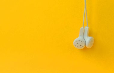 Beyaz modern kulaklık parlak bir turuncu arka plan asılı. Müzik dinleme hayranları için bir şablon