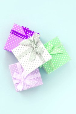 Küçük renkli hediye kutuları şeritler yığını mor bir arka plan üzerinde yatıyor. Üstten görünüm minimalizm düz yatıyordu.