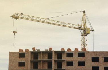 İnşaat halindeki binaları ve çok katlı evleri olan büyük bir şantiye manzarası. Mavi gökyüzü arka planında kule vinçleri devrede. Konut yenileme konsepti. İşlem sırasında turna