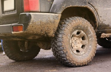 Çamur yolu olan bir kırsal alanda tekerlek yakın çekim. Off-road 4x4 SUV otomobil çamurlu yol alanında sürdükten sonra ditry body ile